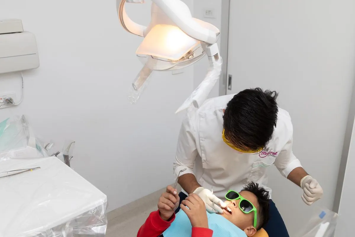 A young child wearing fun green sunglasses having a relaxed dental check-up with a Magical Smiles dentist.