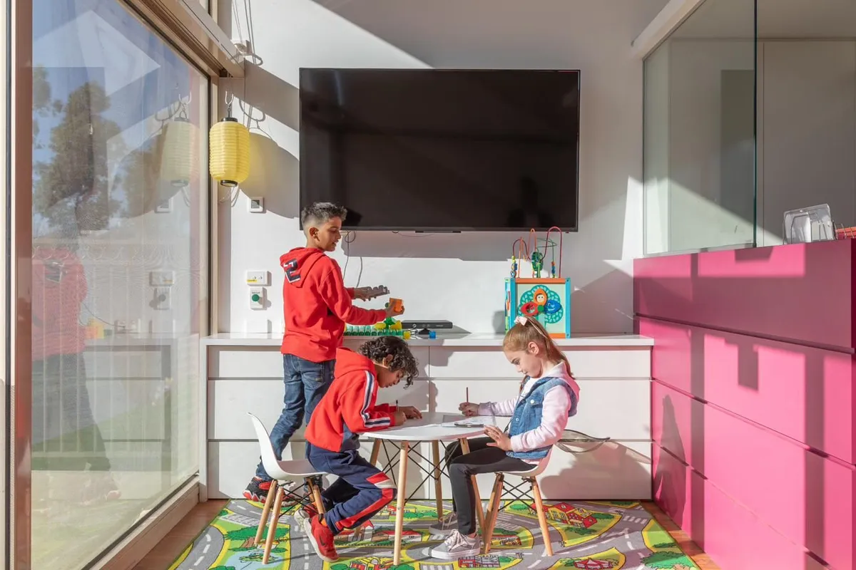 Three young children drawing at a small table in the Caroline Springs clinic's kids area, with toys and an activity cube nearby.