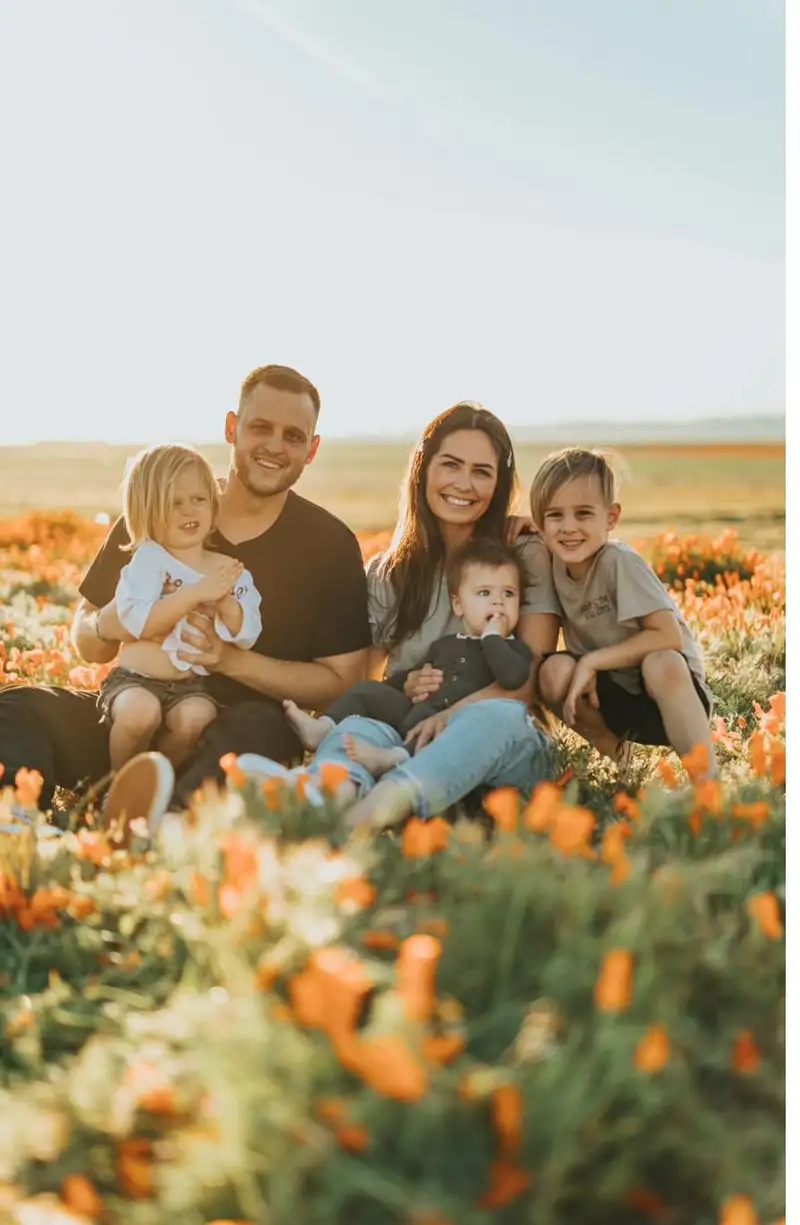 A warm family scene with parents and three children outdoors at sunset — gentle, calm, family-focused.