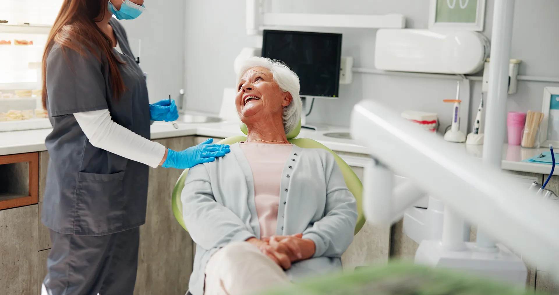 A senior woman laughing with her dentist during a check-up