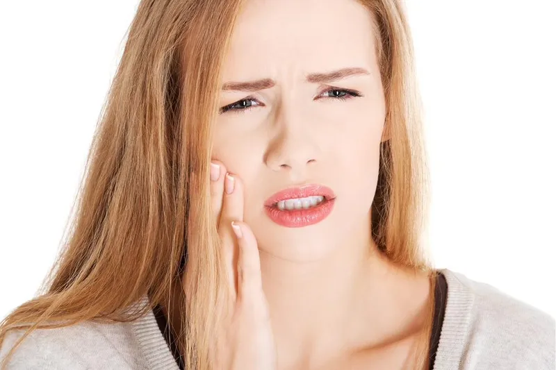 An adult holding their cheek, experiencing tooth pain