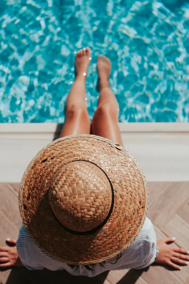 Person sitting at the edge of a pool with their feet dipped in the water on holiday, evoking the deeper, drowsy calm of oral sedation