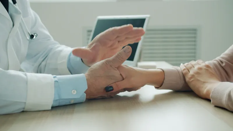 Clinician speaking calmly with a patient, a reassuring hand resting gently on their arm as they talk through what to expect