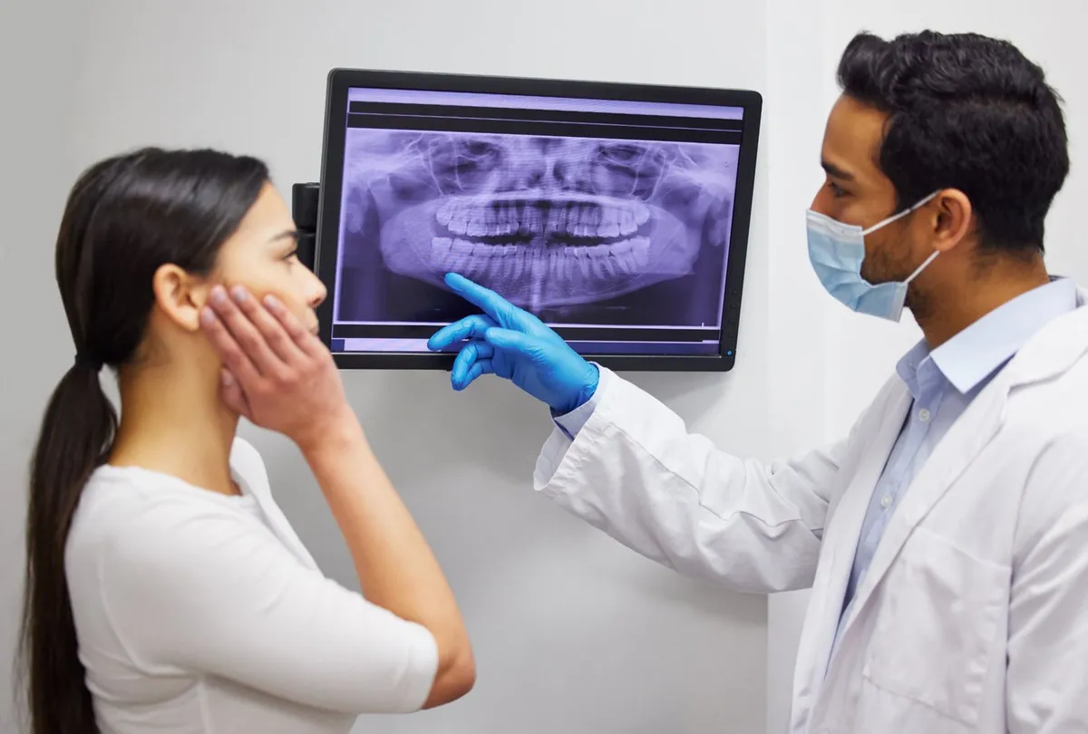 Magical Smiles dentist pointing out the wisdom teeth on a patient's panoramic X-ray
