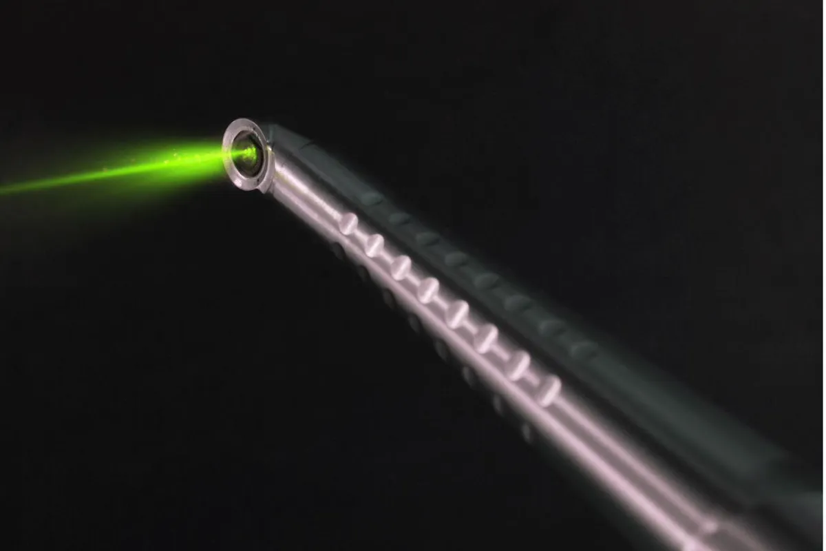 Close-up of the Er:YAG laser tip projecting a focused green beam against a black background
