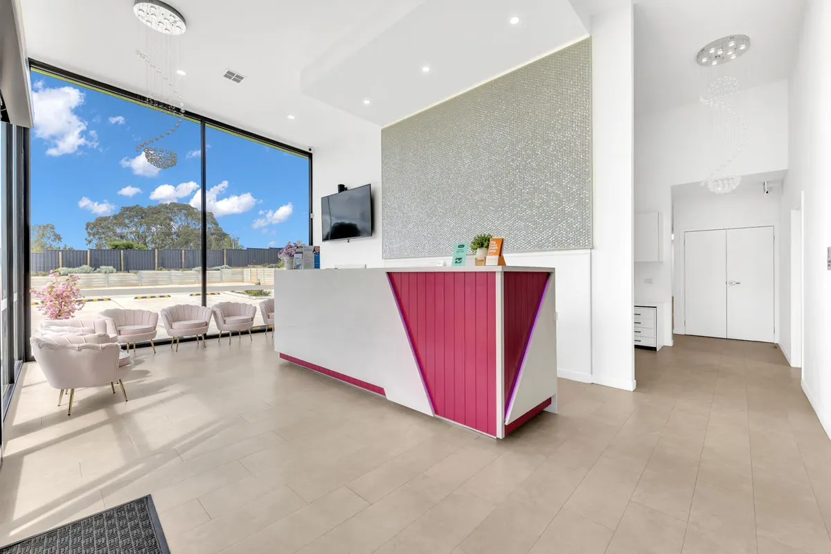 Reception and waiting area at Magical Smiles Caroline Springs — natural light through the front windows, soft cream-toned tile floor, lounge seating in the corner