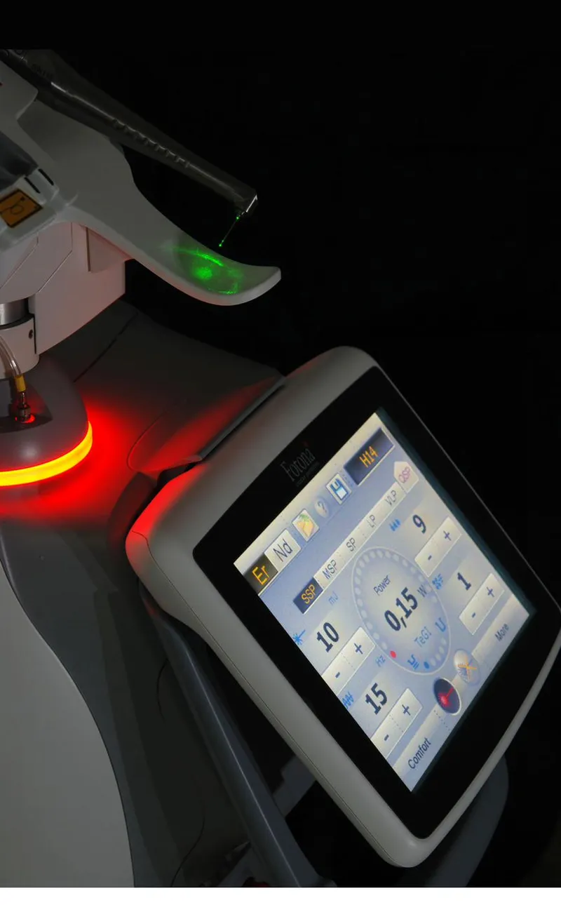 Fotona LightWalker dental laser unit with the green aiming beam visible on the handpiece and the dual-wavelength control screen displaying Er:YAG and Nd:YAG parameters