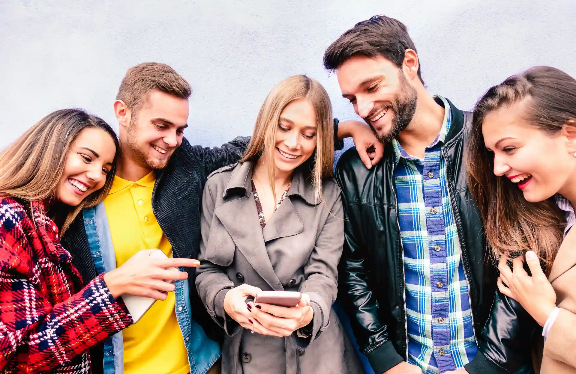 A group of friends laughing together while looking at a phone
